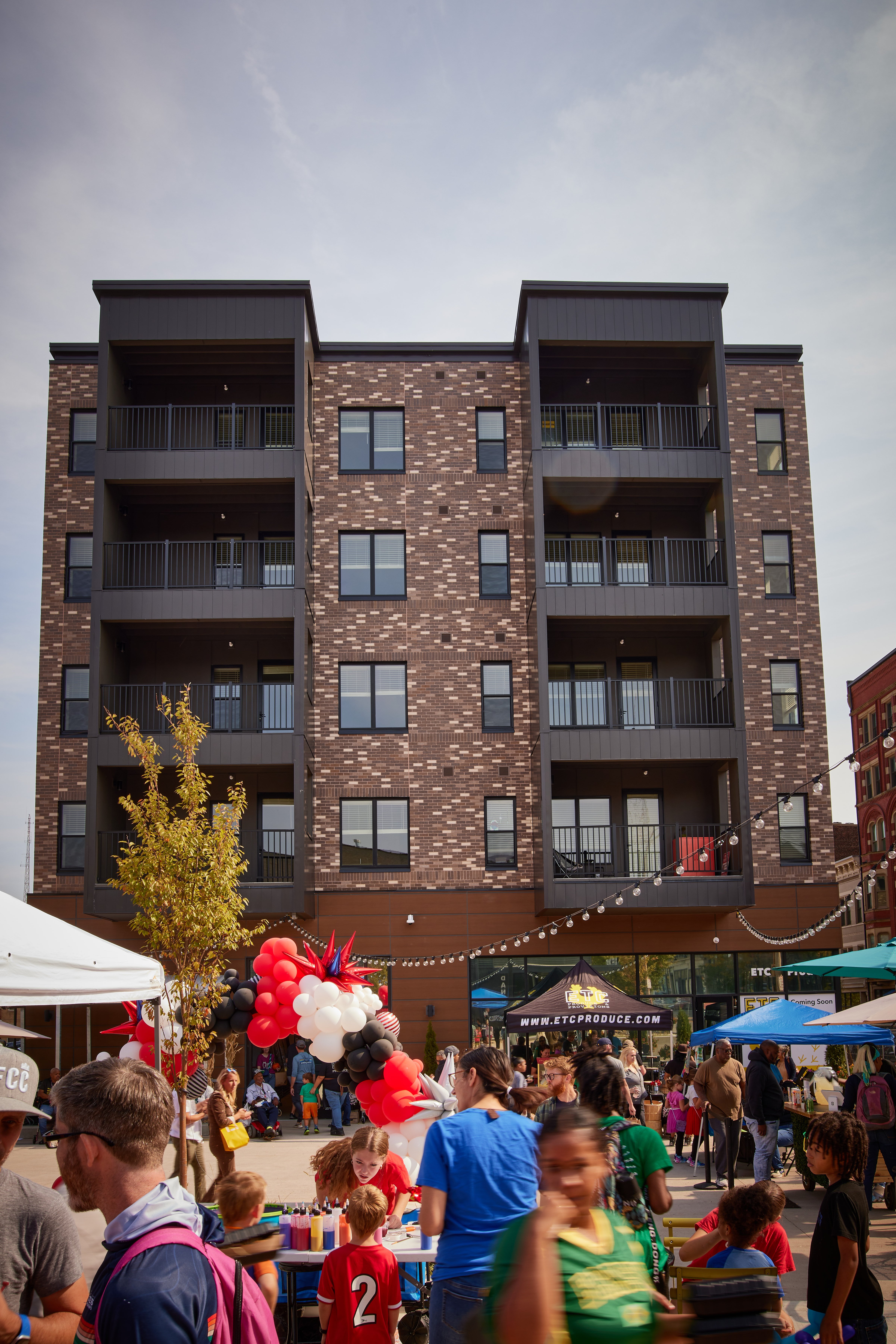 A large building with balconies is behind a crowd of people.